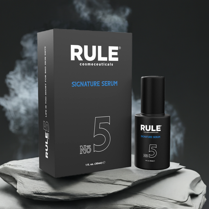 Rule Cosmeceuticals No. 5 Signature Serum bottle and box placed on sleek, textured stone with a dark and elegant backdrop. A premium skincare product for deep hydration and wrinkle reduction.