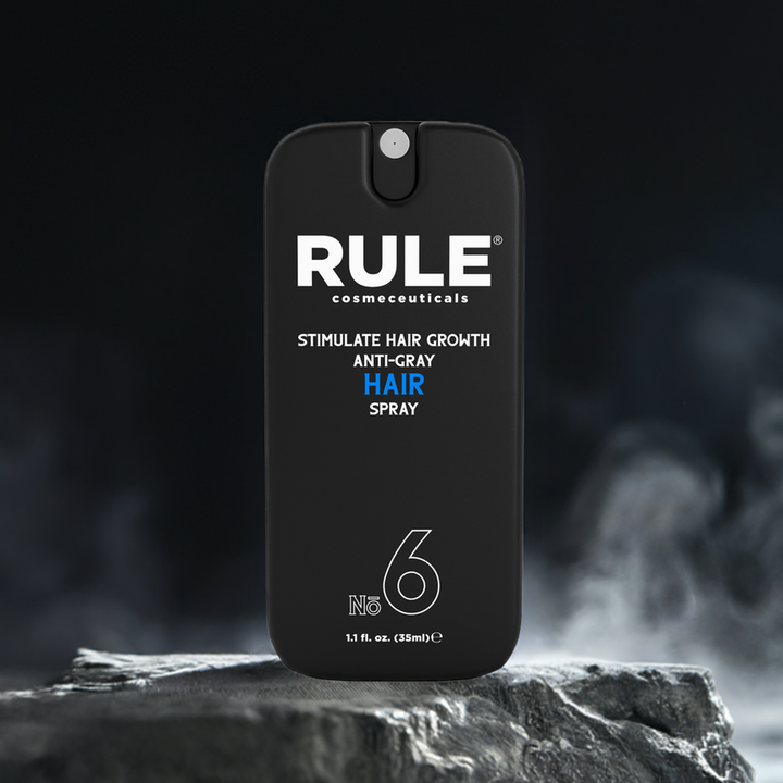 Rule Cosmeceuticals No. 6 Anti-Gray Hair Spray bottle displayed on a rugged stone platform with a dark, misty background. A cutting-edge product for stimulating hair growth and reducing grey hair.