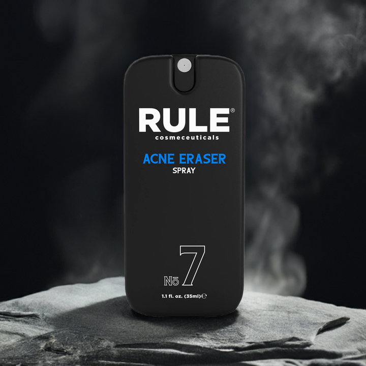 Rule Cosmeceuticals No. 7 Acne Eraser Spray bottle displayed on a textured stone surface with a dark, misty backdrop. A streamlined solution for targeting acne and promoting clear skin.